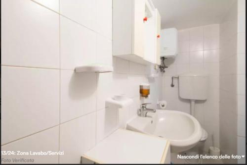 a white bathroom with a toilet and a sink at Locazione Turistica Monolocale nel Parco del Santuario in Asti