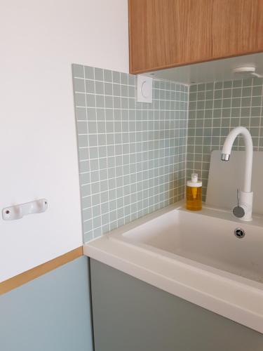 La salle de bains est pourvue d'un lavabo blanc et de carrelage vert. dans l'établissement Appartement de charme vue mer, à Deauville