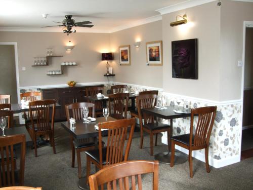 Grove House Hotel في وودبريدج: غرفة طعام مع طاولات وكراسي وبار