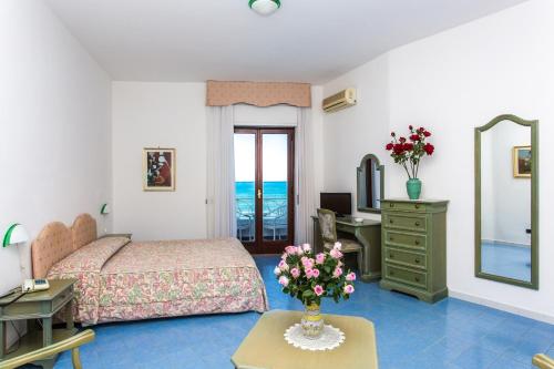 a bedroom with a bed and a table with flowers on it at Hotel Poseidon in Diamante