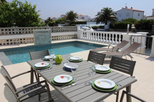 エンプリアブラバにあるApart-rent Casa con piscina Flamicell 0042のプールサイドのテーブル(皿付)とワイングラス