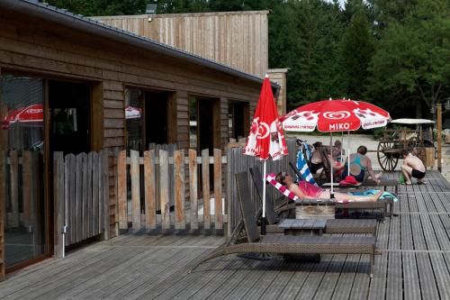 a group of people sitting in chairs under an umbrella on a deck at Etangs du Moulin in Suzy
