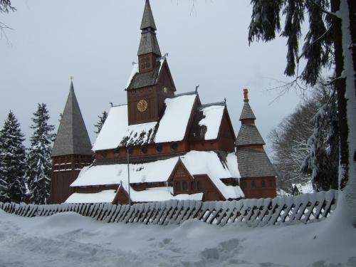 un grand bâtiment avec une tour d'horloge dans la neige dans l'établissement Ferienwohnungen Haus am Karpfenteich, à Hahnenklee