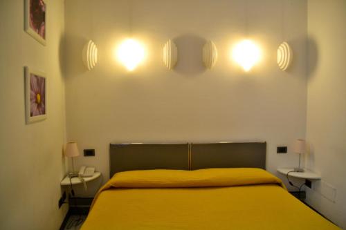 a bedroom with a yellow bed with lights on the wall at Hotel Italia in Foligno