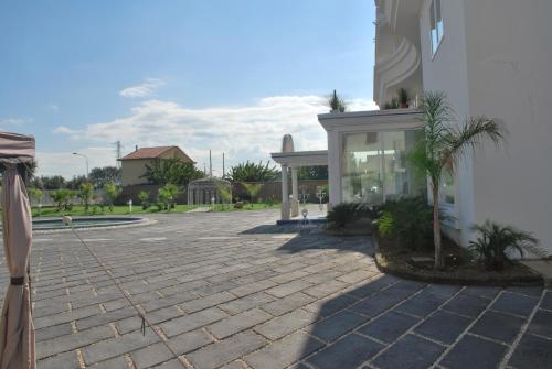 a courtyard with a building and a palm tree at Hotel The Queen in Pastorano
