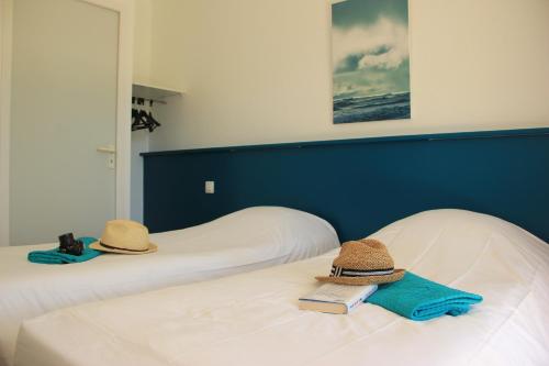 deux lits avec des chapeaux et un livre dessus dans l'établissement Village Vacances Les Dunes - Domaine de Bombannes, à Carcans
