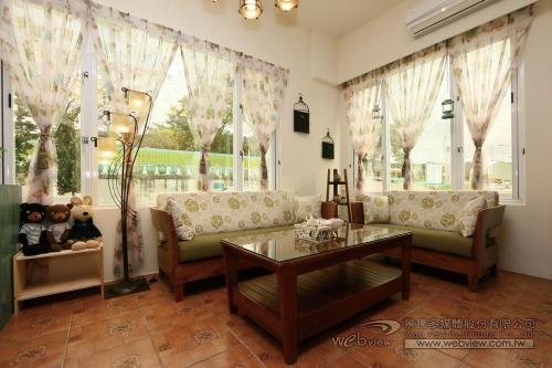 a living room with a couch and a table and windows at Bear Homestay in Taitung City