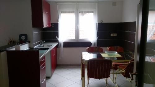 una cucina con mobili rossi, un tavolo e una finestra di Apartment Krsmanovic a Arandjelovac