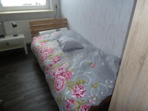 ein Bett mit einer Blumendecke und Kissen darauf in der Unterkunft im gelben Haus in Trusen