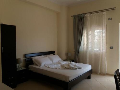 1 dormitorio con 1 cama con sábanas blancas y ventana en Villa Nicolaos Ksamil, en Ksamil