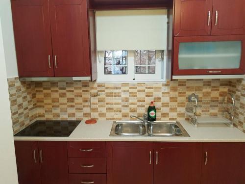 a kitchen with red cabinets and a sink at Villa Nicolaos Ksamil in Ksamil