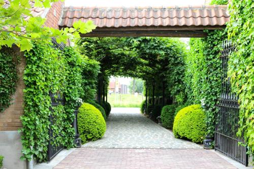an entrance to a garden with an arch covered in ivy at B&B Hof te Spieringen in Vollezele