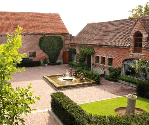 un patio con una fuente frente a un edificio en B&B Hof te Spieringen en Vollezele