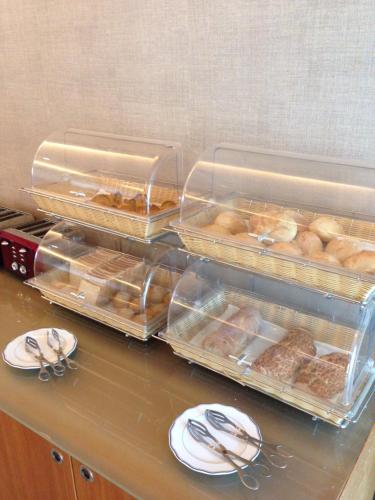 two trays of donuts sitting on a counter with plates at Hotel Suave Mar in Esposende