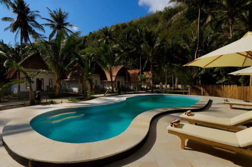 a swimming pool with two chairs and an umbrella at Crystal Bay Villa & Residence in Nusa Penida