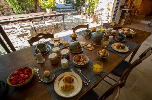 a wooden table with breakfast food on it at Le Jas de Péguier in Châteauneuf-Val-Saint-Donat
