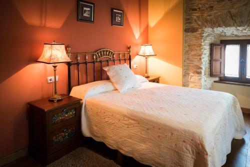 a bedroom with a bed and two lamps on a table at Hotel Rural Casona Trabadelo in Vegadeo