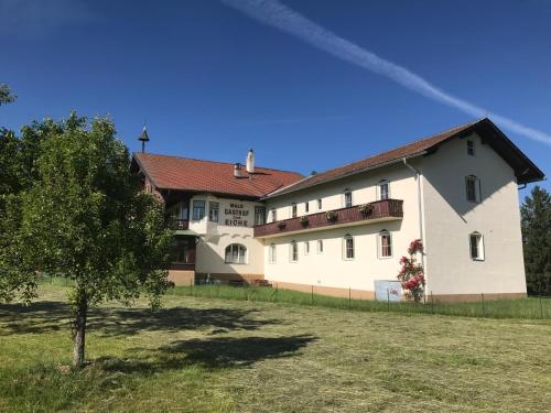 a large white building with a tree in a field at Landhotel Gasthof Eichhof Natters in Innsbruck
