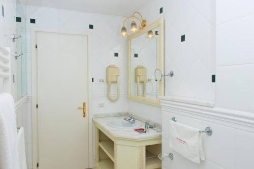 a white bathroom with a sink and a mirror at Hotel Universal Terme in Abano Terme