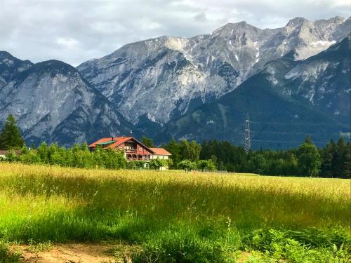 a house in a field with mountains in the background at Landhotel Gasthof Eichhof Natters in Innsbruck