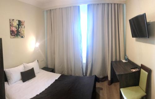 a bedroom with a bed and a desk and a window at Non-stop Economy hotel in Boryspilʼ