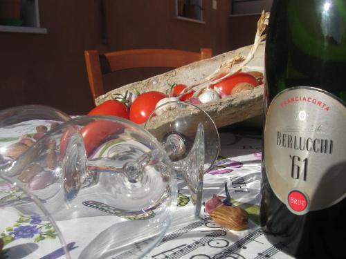 a table with a bottle of wine and a basket of tomatoes at VALDERICE VACANZE biker's friend in Valderice