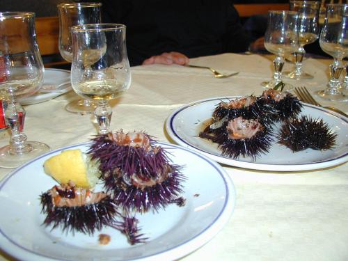 three plates of food on a table with wine glasses at La Casa di Ulisse B&B in Quercianella