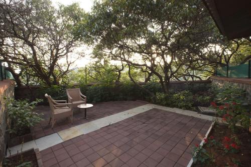 a patio with a chair and a table and some trees at Ramsukh Resorts and Spa in Mahabaleshwar