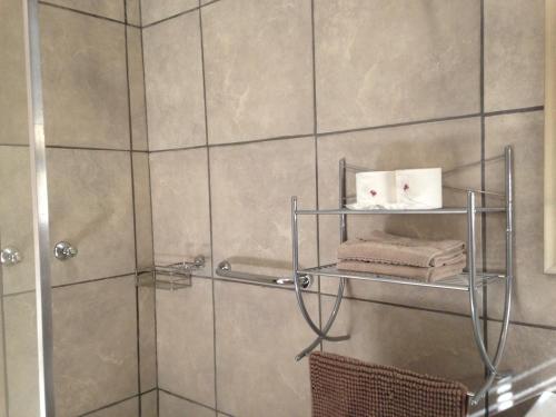 La salle de bains est pourvue d'une douche et de 2 serviettes sur une étagère. dans l'établissement Impala Chalets, à Phalaborwa