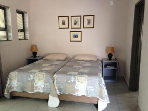 a bedroom with two beds and two lamps at Impala Chalets in Phalaborwa