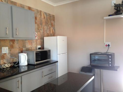a kitchen with a white refrigerator and a microwave at Impala Chalets in Phalaborwa