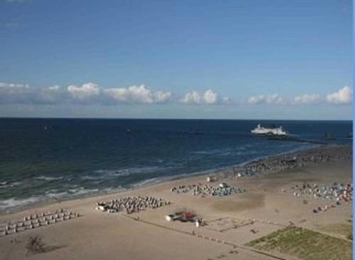 een strand met een grote groep mensen en een boot in het water bij RN_Ferienwohnungsvermietung _ Obje in Warnemünde