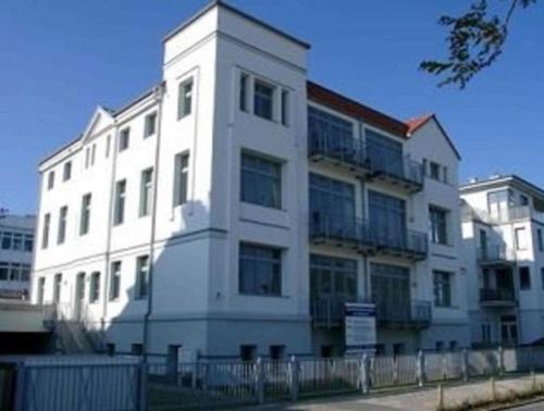 een wit gebouw met een hek ervoor bij RN_Ferienwohnungsvermietung _ Obje in Warnemünde