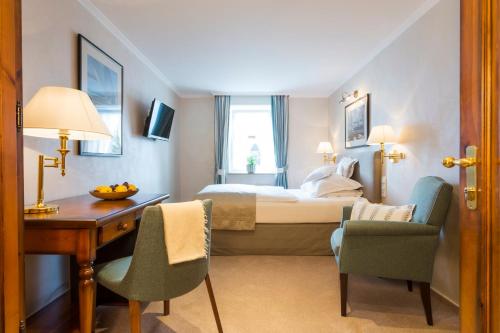 a hotel room with a bed and a desk and chairs at Romantik Berghotel Astenkrone in Winterberg
