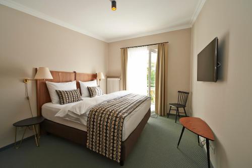 Habitación de hotel con cama y TV en Parkhotel Obermenzing en Múnich