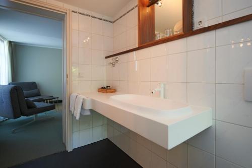 a bathroom with a large white sink and a chair at Parkhotel Obermenzing in Munich