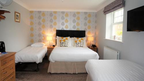 a bedroom with two beds and a tv at The Lawn Guest House Gatwick in Horley