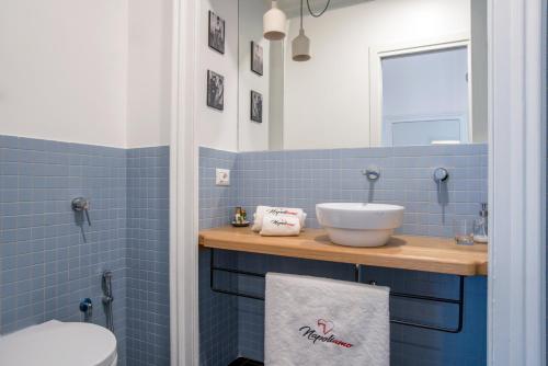 a blue tiled bathroom with a sink and a toilet at Napoliamo Guest House in Naples