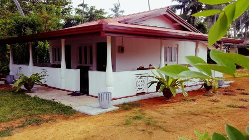 a small white house with a red roof at Anura Home Stay in Kalutara