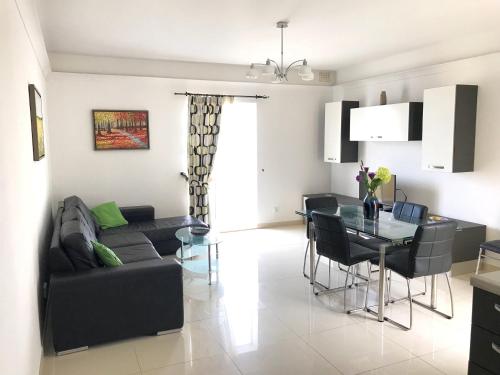 a living room with a black couch and a table at Savoy in St Paul's Bay