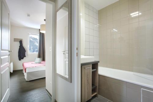 a white bathroom with a tub and a sink at Résidence Odalys Le Village de Praroustan in Pra-Loup