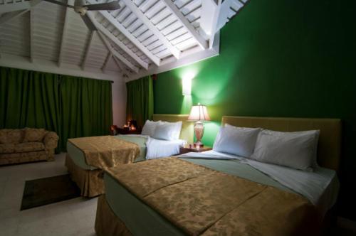 um quarto com 2 camas e uma parede verde em Mynt Retreat Bed & Breakfast em Montego Bay