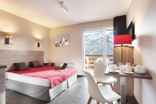 um quarto com uma cama, uma mesa e cadeiras em Résidence Odalys Le Village de Praroustan em Pra-Loup
