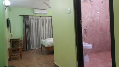 - une salle de bains avec toilettes et un lit dans une chambre dans l'établissement Hotel Bishram, à Pokhara