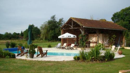 a pavilion with a table and chairs next to a pool at Country Farmhouse with pool in Lascazères