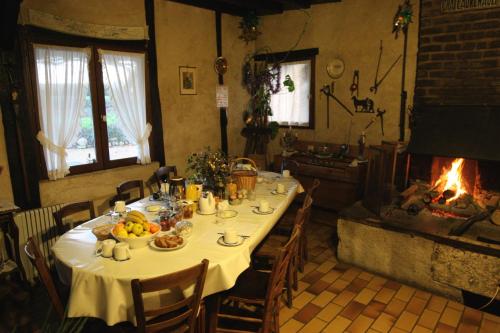 a dining room with a table and a fireplace at La Maréchalerie in Monthodon