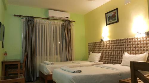 um quarto de hotel com duas camas e uma janela em Hotel Bishram em Pokhara