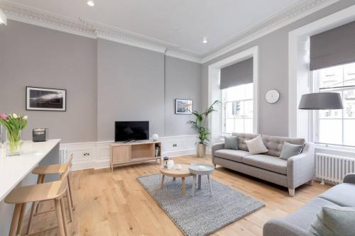a white living room with a couch and a table at JOIVY Spacious Apartment close to Princes Street in Edinburgh