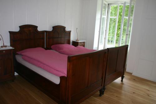 Schlafzimmer mit einem Holzbett mit rosa Bettwäsche in der Unterkunft Hôtel de la Truite in Champ-du-Moulin