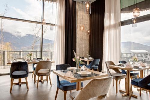 a restaurant with tables and chairs and a large window at Tarcin Forest Resort & Spa Sarajevo - MGallery Collection in Tarčin